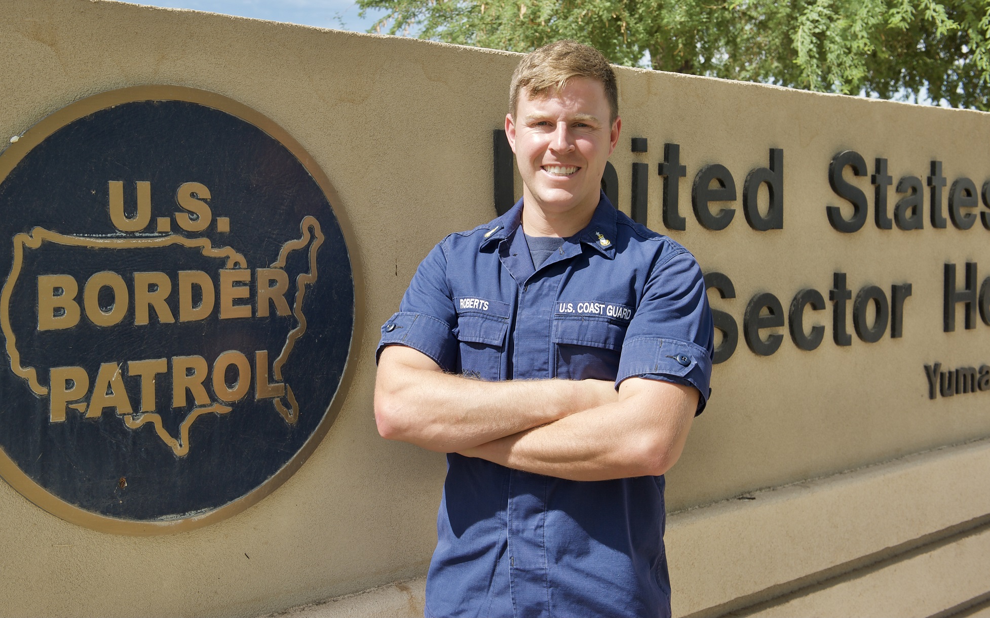 Senior Chief Petty Officer Travis L. Roberts, a health services technician, assigned to Port Security Unit Fort Eustis, Va. and currently mobilized to provide logistical and medical support at the Southwest Border for U.S. Customs and Border Protection, stands in front of the Border Patrol Sector Yuma Headquarters, Arizona, July 21, 2021, after being recognized with the Master Chief Petty Officer Angela M. McShan Inspirational Leadership Award. Photo By: Petty Officer 2nd Class Brandon Hillard. 